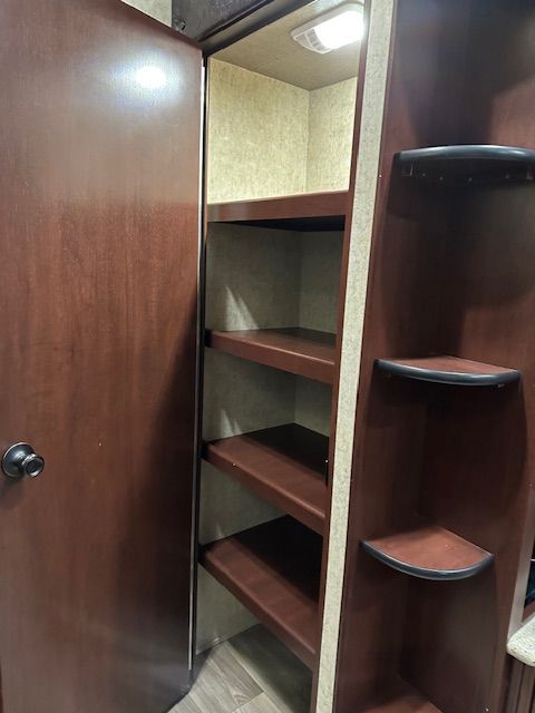 Dark wood storage cabinet with shelves and a closet door.