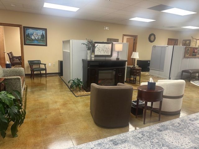 A waiting room with chairs, a fireplace console, and office partitions under recessed lighting.