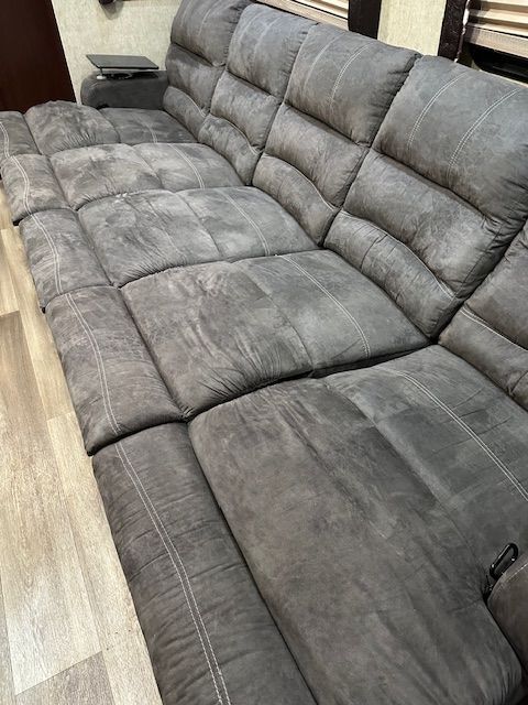 Gray sectional sofa with tufted cushions in an interior setting.