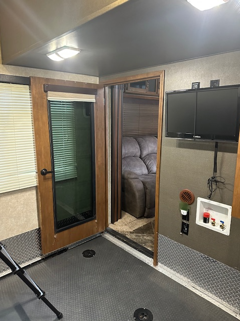Interior view of a toy hauler garage with a door to the living area, a TV, and a washer/dryer hookup.