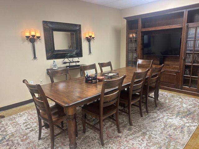 Dining room with long wooden table, eight chairs, decorative mirror, and built-in shelving.