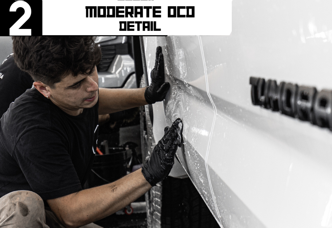 A person in gloves applying a protective film on a white truck. Text: Moderate OCD Detail.