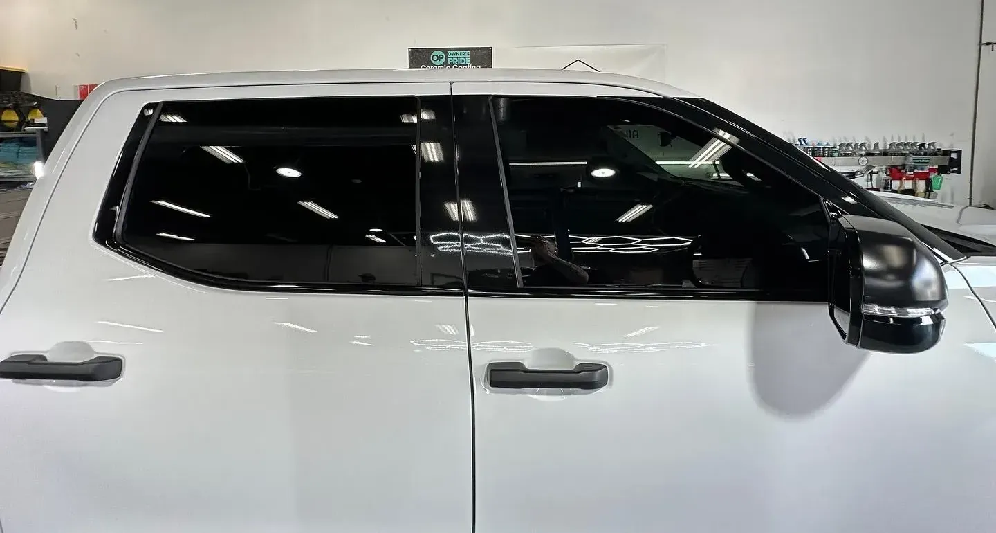 A white truck with black windows is parked in a garage.