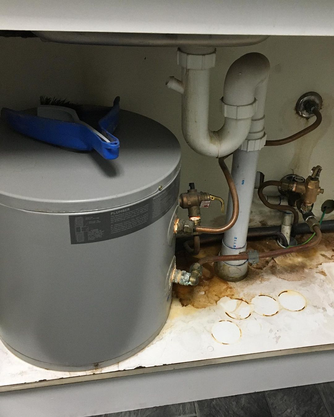 A water heater is under a sink in a kitchen.