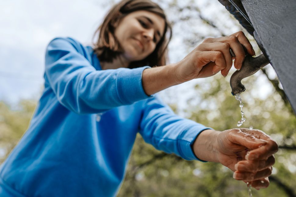 A person stopping an outdoor water tap likely causing water hammer