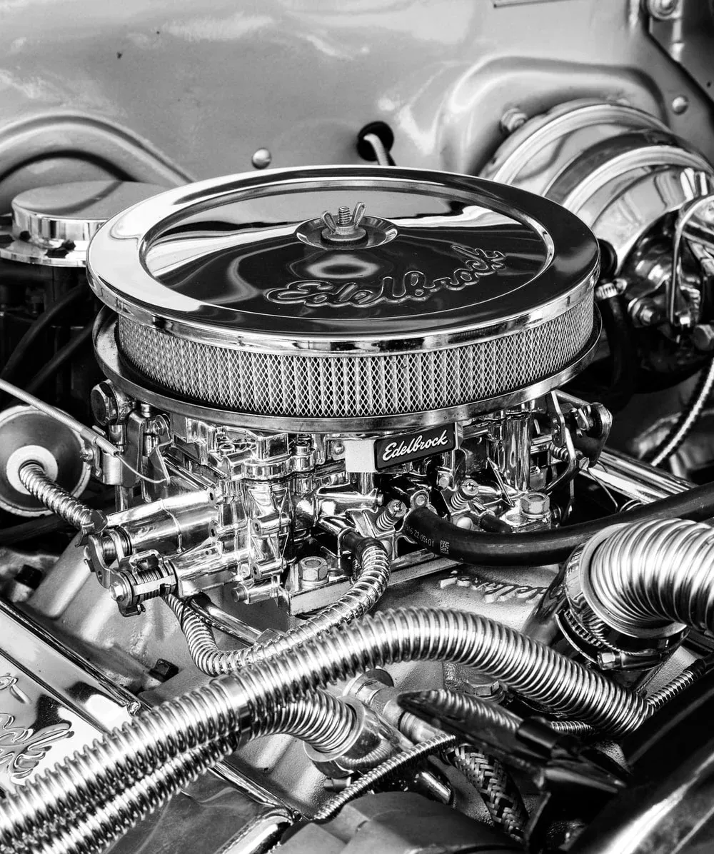 Close-up of a chrome car engine with a round air filter and braided hoses