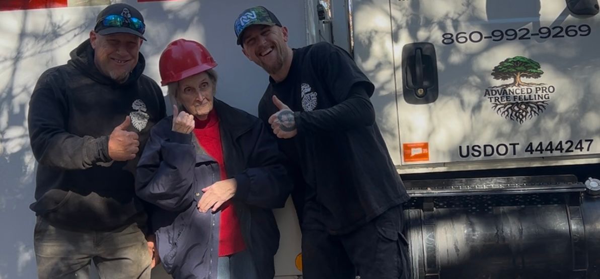 Three people smiling and posing beside a white truck with a company logo.