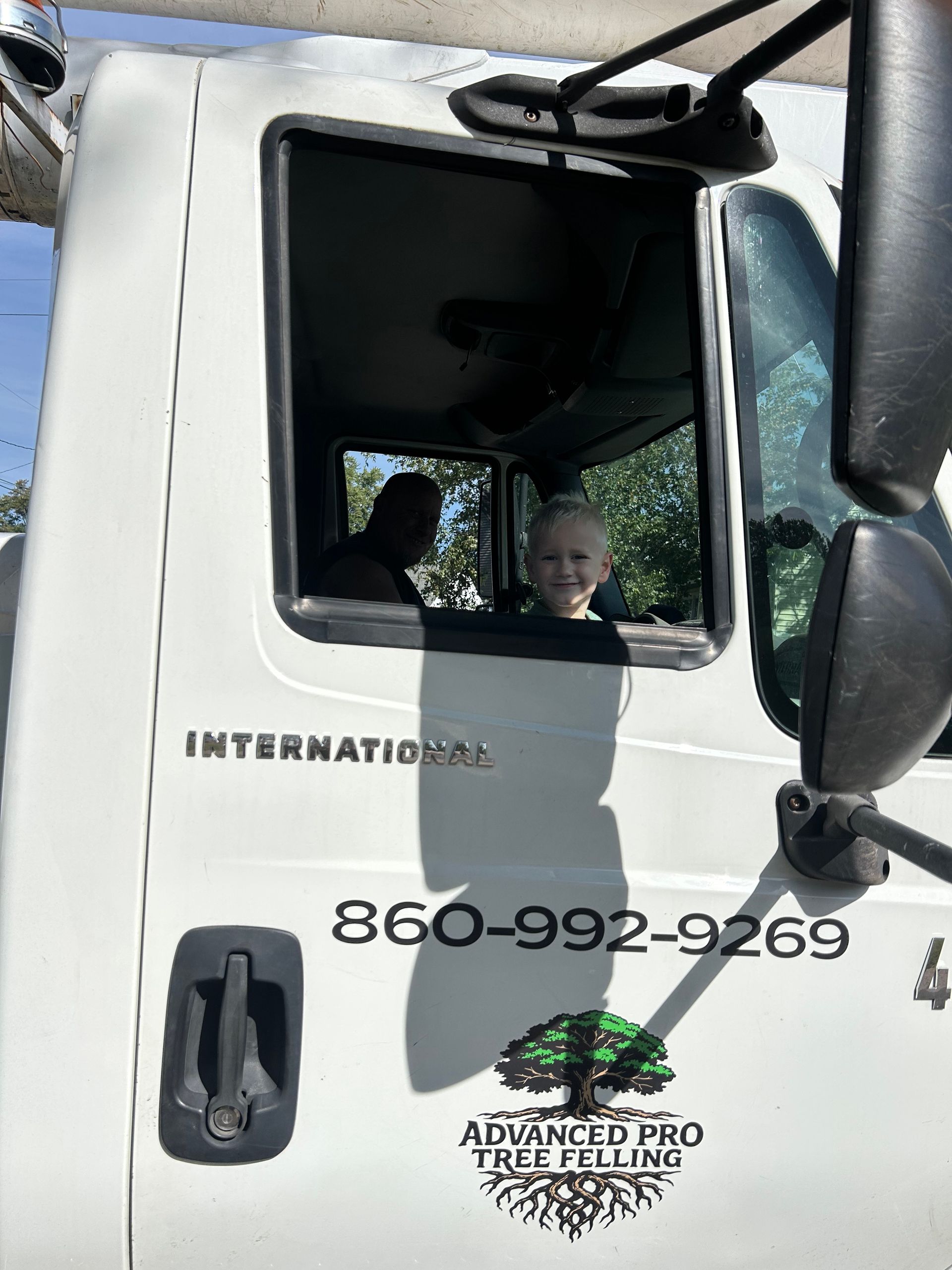 White truck cab with two people visible through the window and company logo on the door.