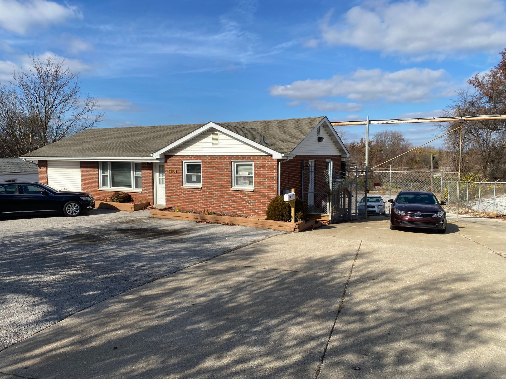 A brick house with cars parked in front of it on a sunny day.