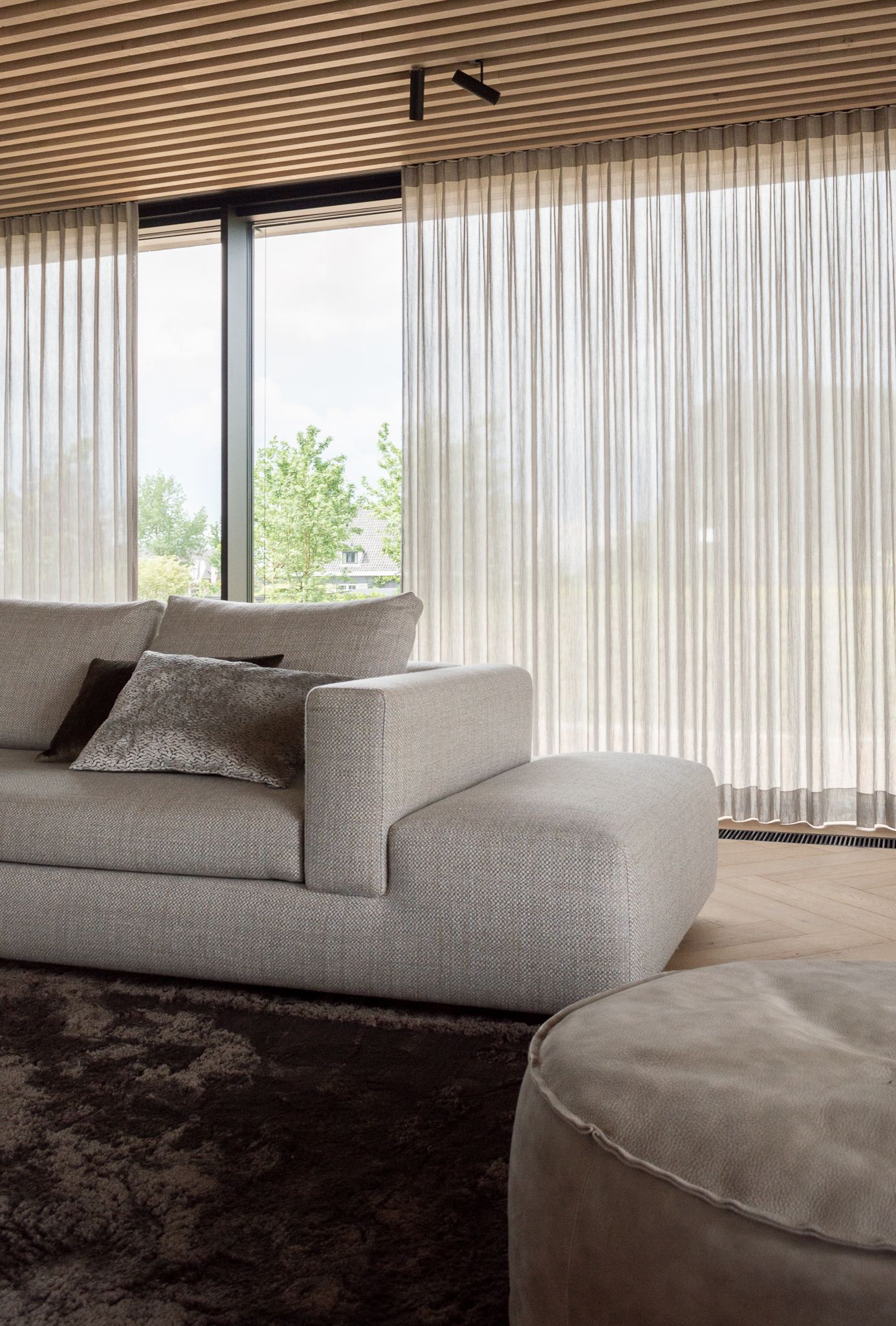Een woonkamer met bank Me Time van Sur&Plus  grote ramen.