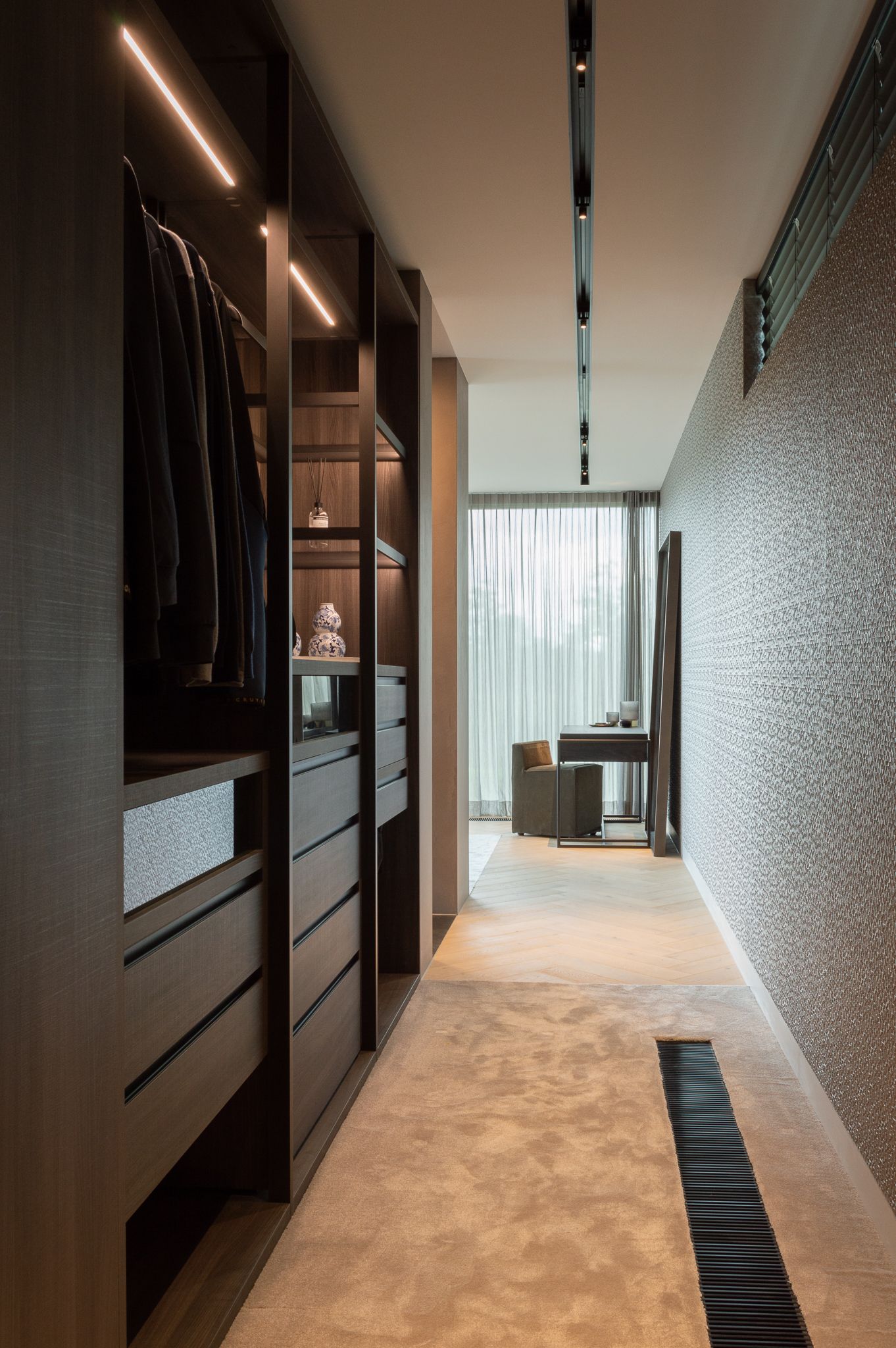 Een inloopkast van Sangiacomo met veel lades en kleding die naar een slaapkamer leidt. Ontwerp door Woon à la carte.