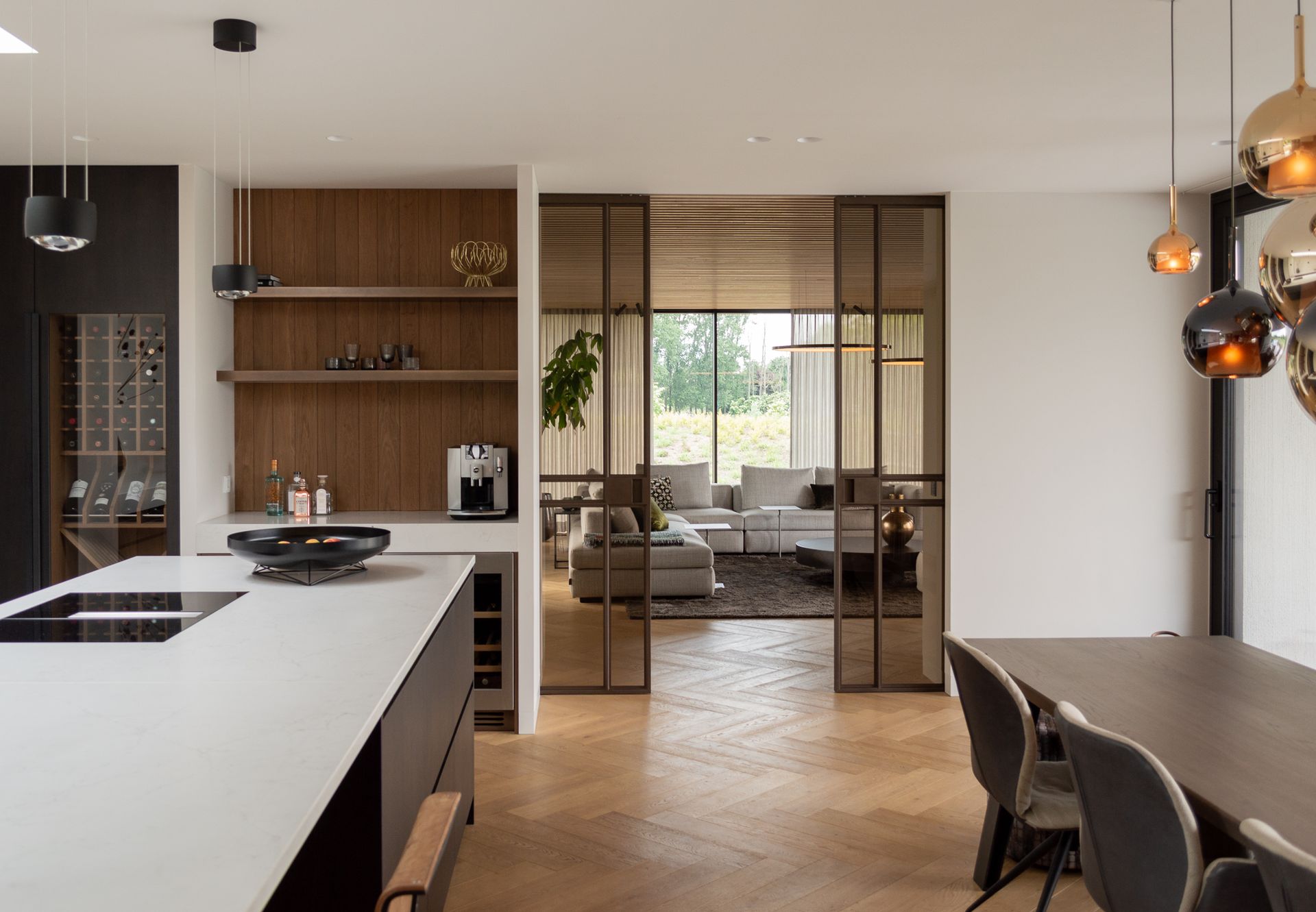 Een keuken met een tafel en stoelen en een glazen schuifdeur van Preferro naar de woonkamer.