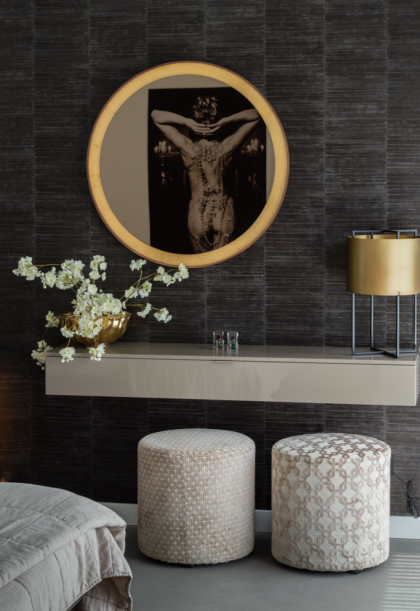 Een slaapkamer met twee poefs en een ronde spiegel