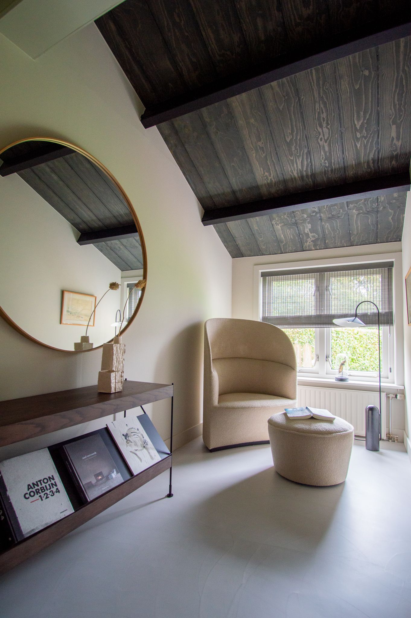 Een woonkamer met een fauteuil van Audi, een voetenbankje, een spiegel en een boekenplank.