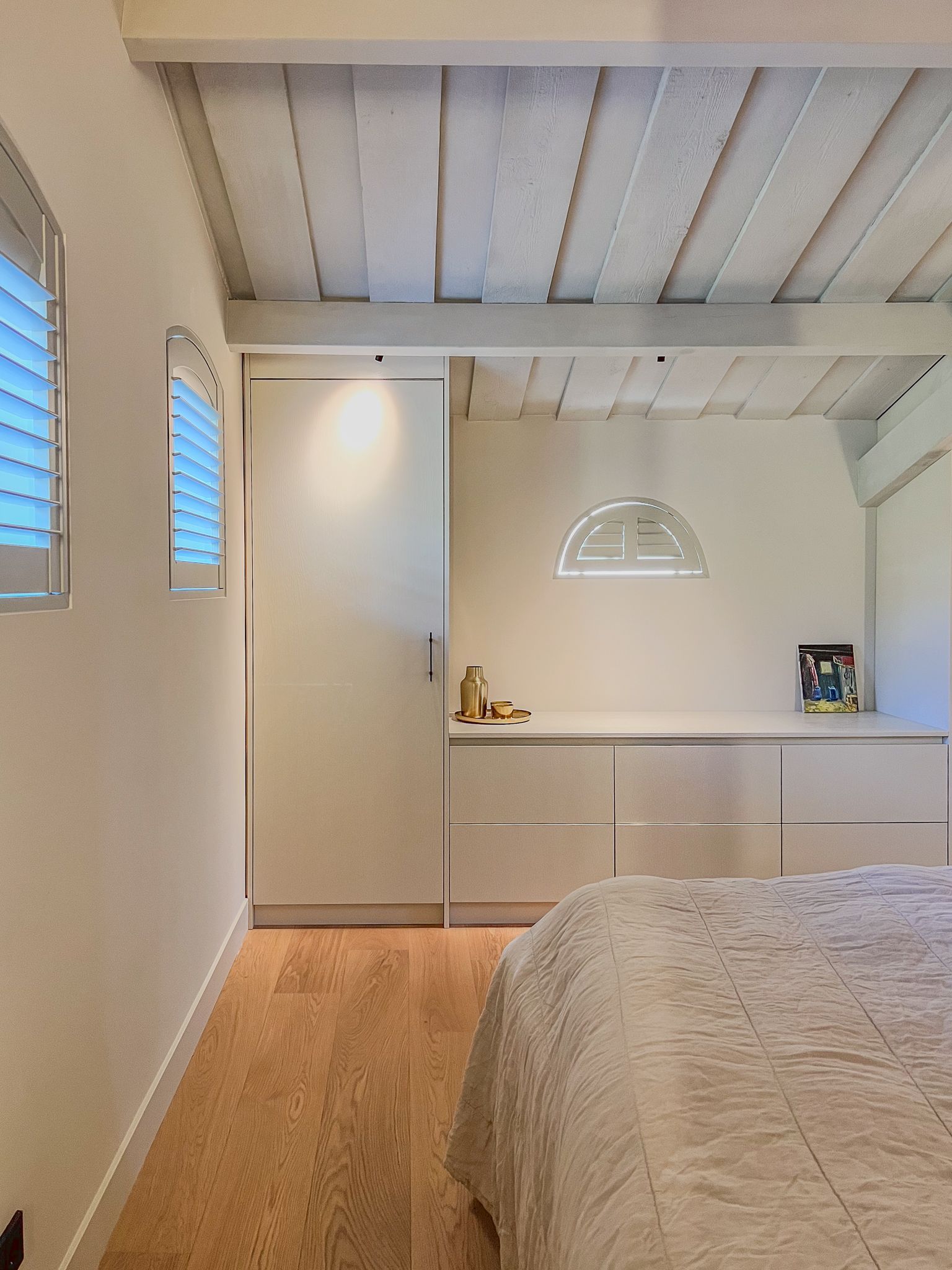 Een slaapkamer met een bed en een maatwerk kast met Jasno Shutters voor de ramen