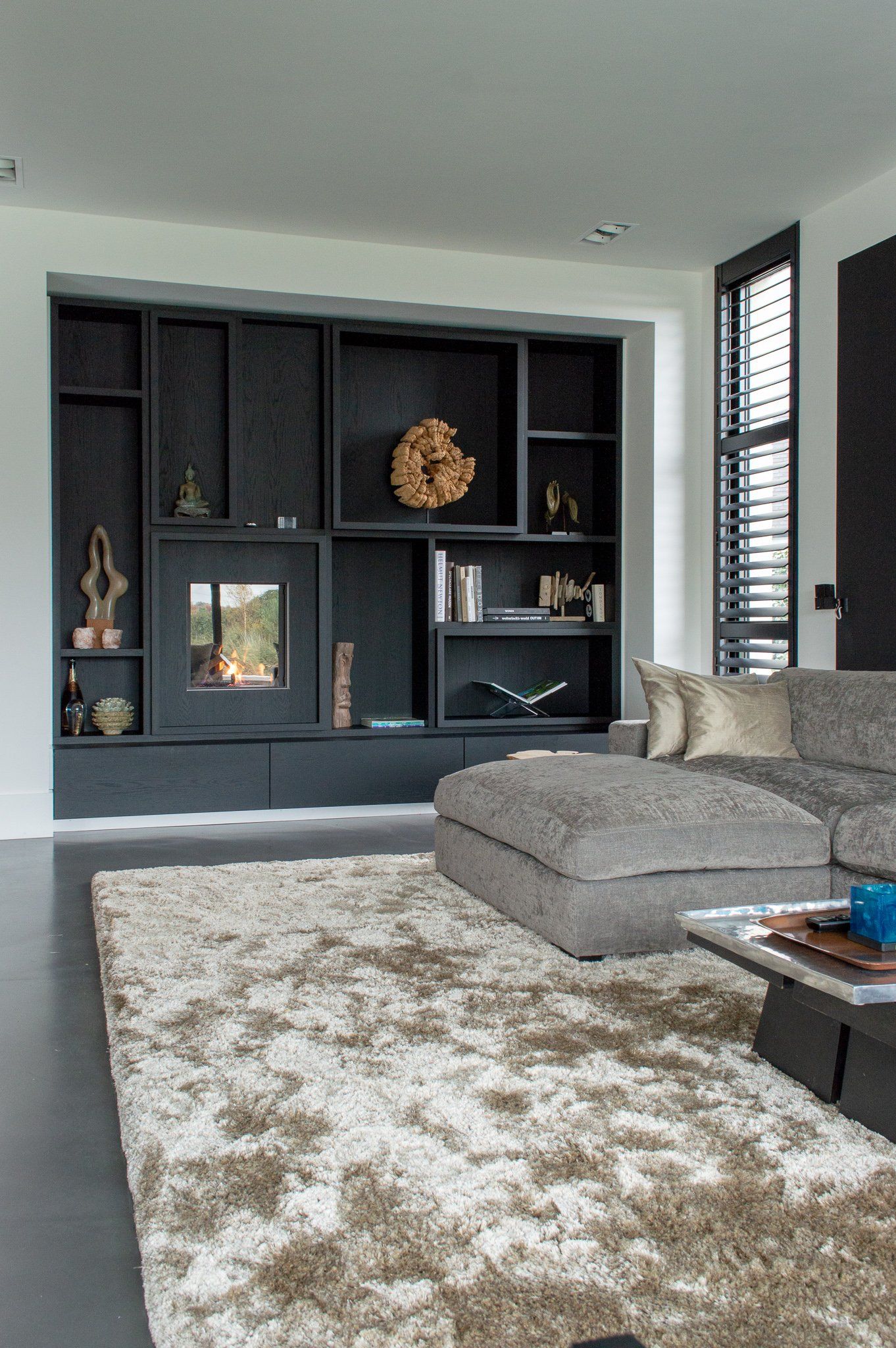 Een woonkamer met een bank, een tapijt en een open haard