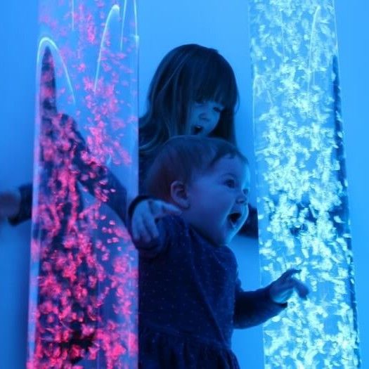 A glowing, cylindrical bubble tube light fixture emitting a bright blue light against a dark blue background.