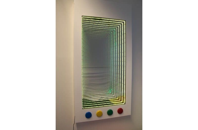 A wall-mounted infinity mirror with four colored buttons—blue, yellow, green, and red—positioned below it.