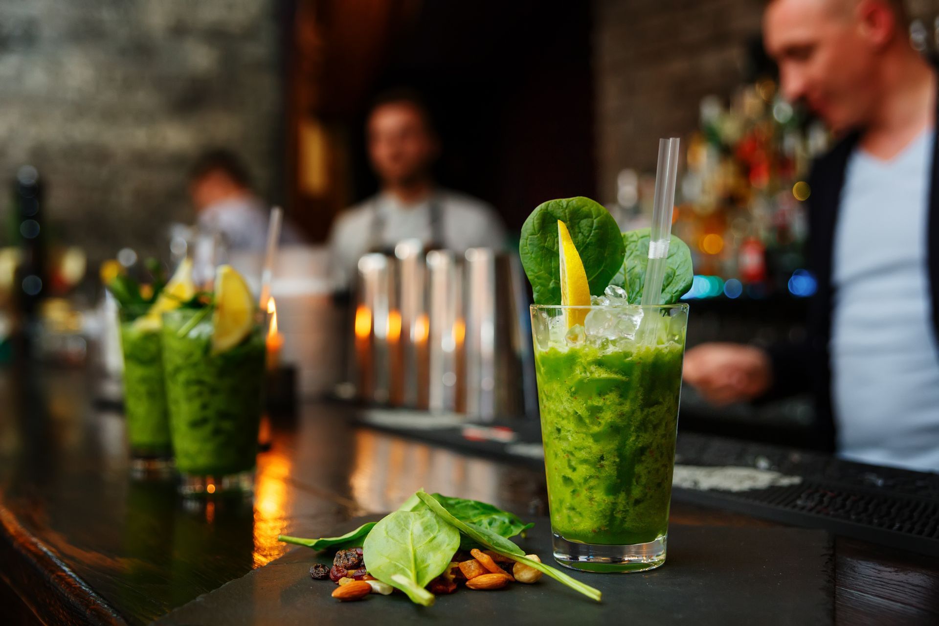 Fresh green cocktail with mint, ice, and lemon garnish served at a bar.