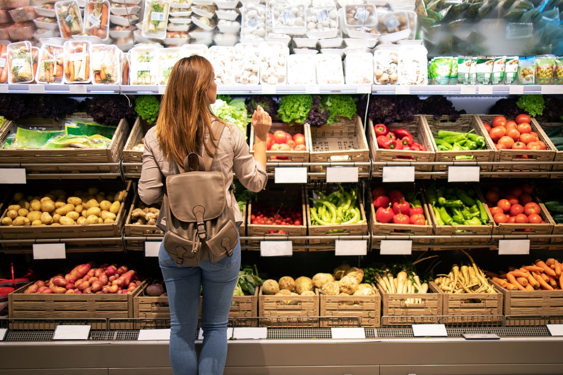 A woman is in front of the vegetable shelves.