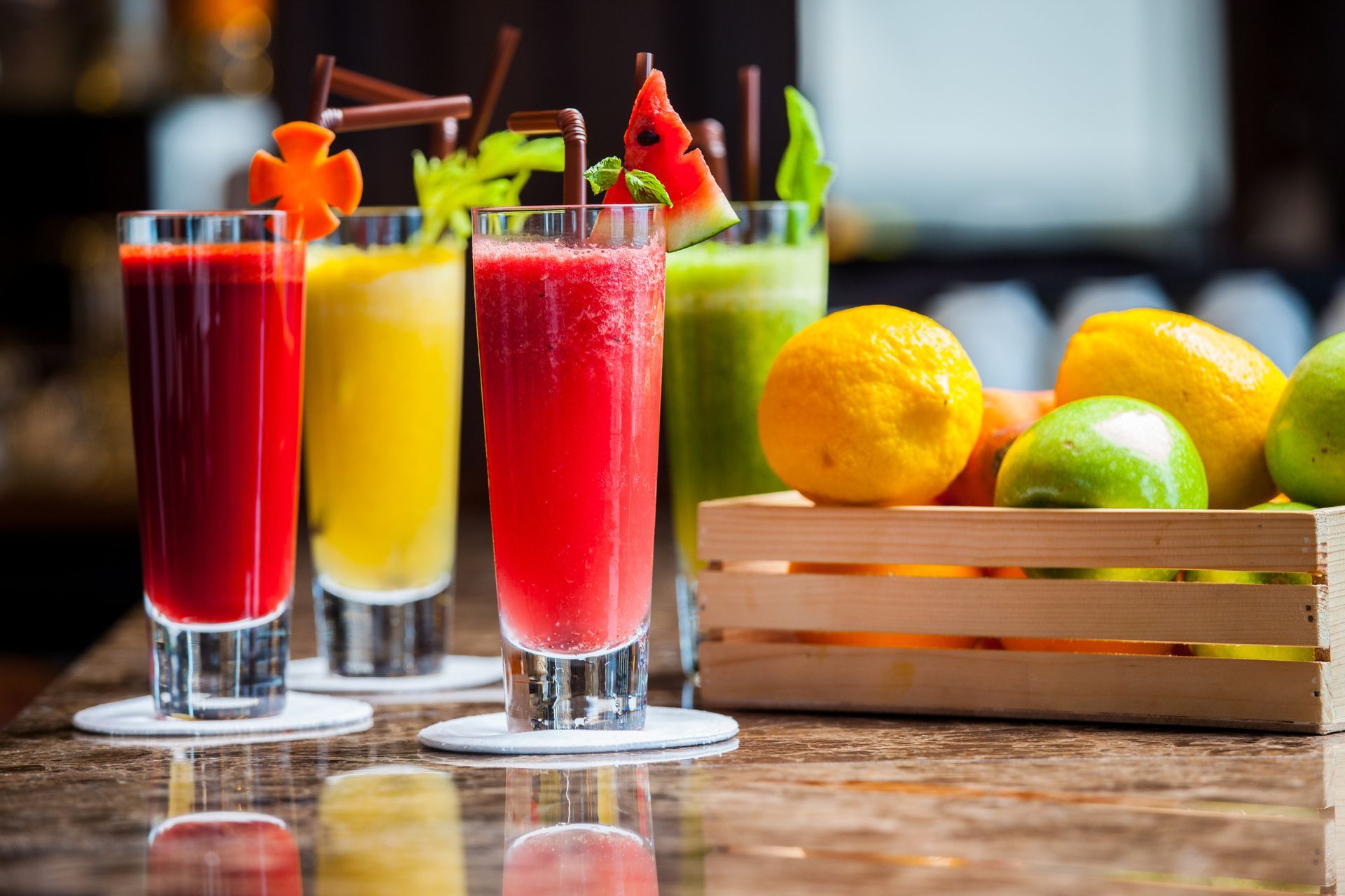 Colorful, fresh drinks at a juice bar with assorted fruits on display.