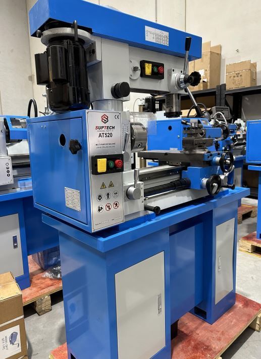 Blue industrial metal lathe in a workshop, with control panel and machine bed on a blue stand.
