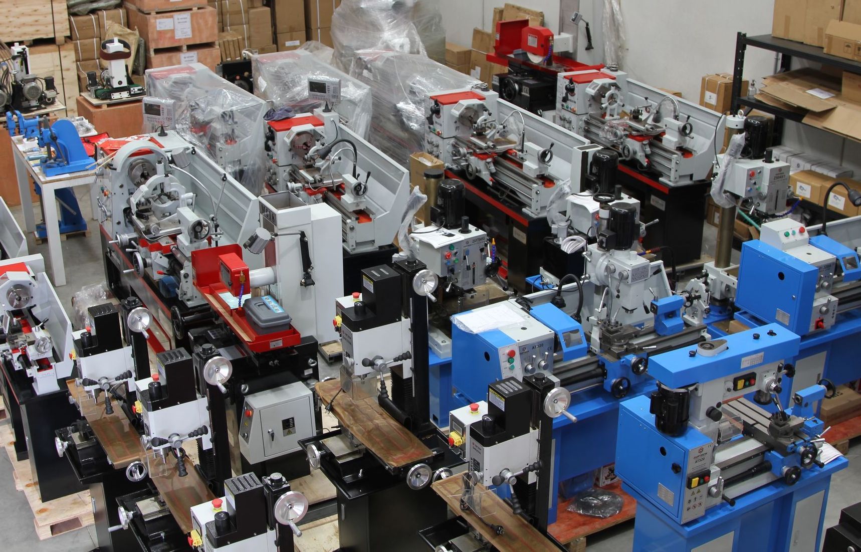 Rows of industrial machines and equipment in a workshop, with blue, red, and gray metal parts.