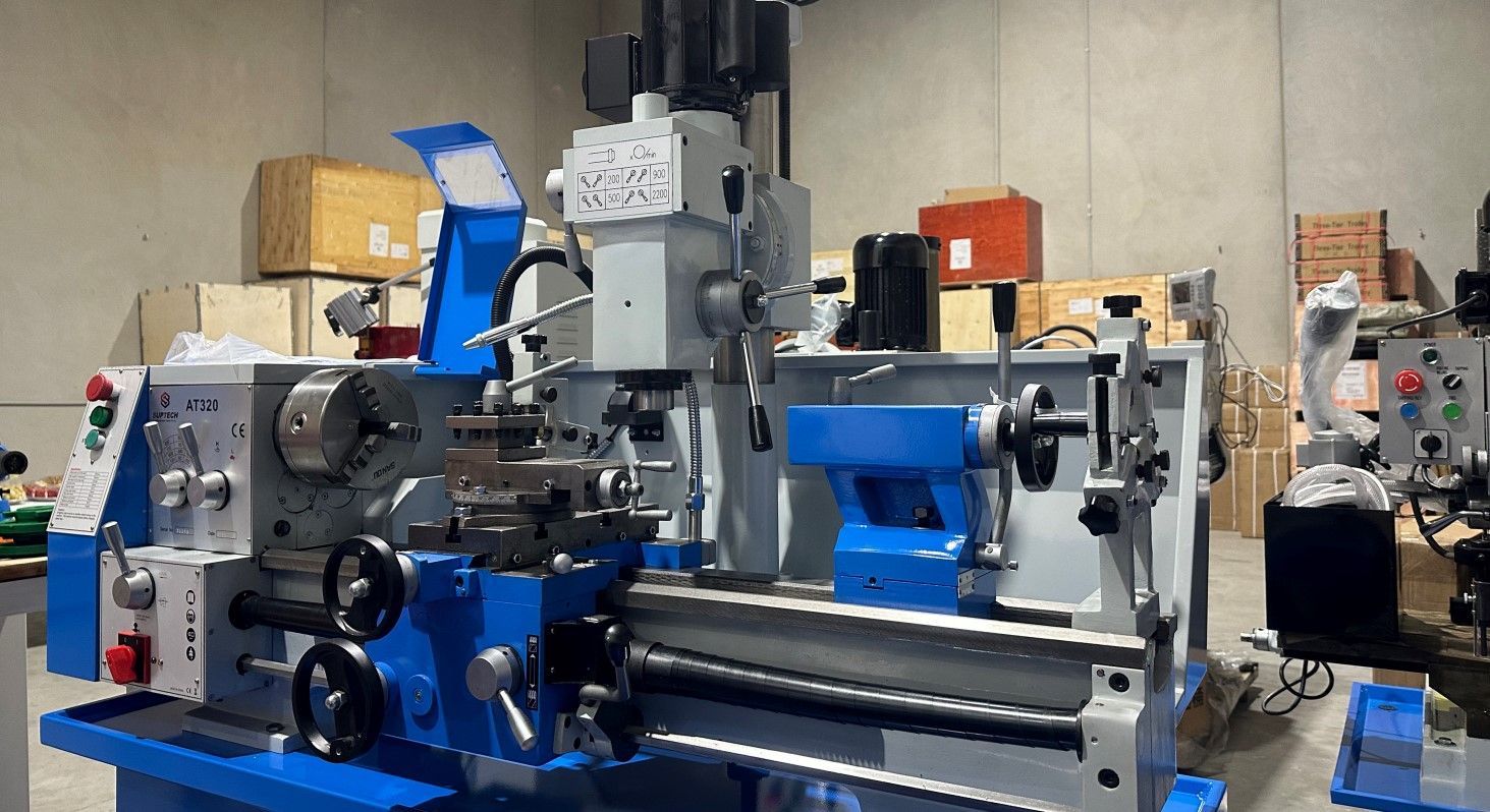 Blue and gray metal lathe machine in a workshop with tools and equipment around it