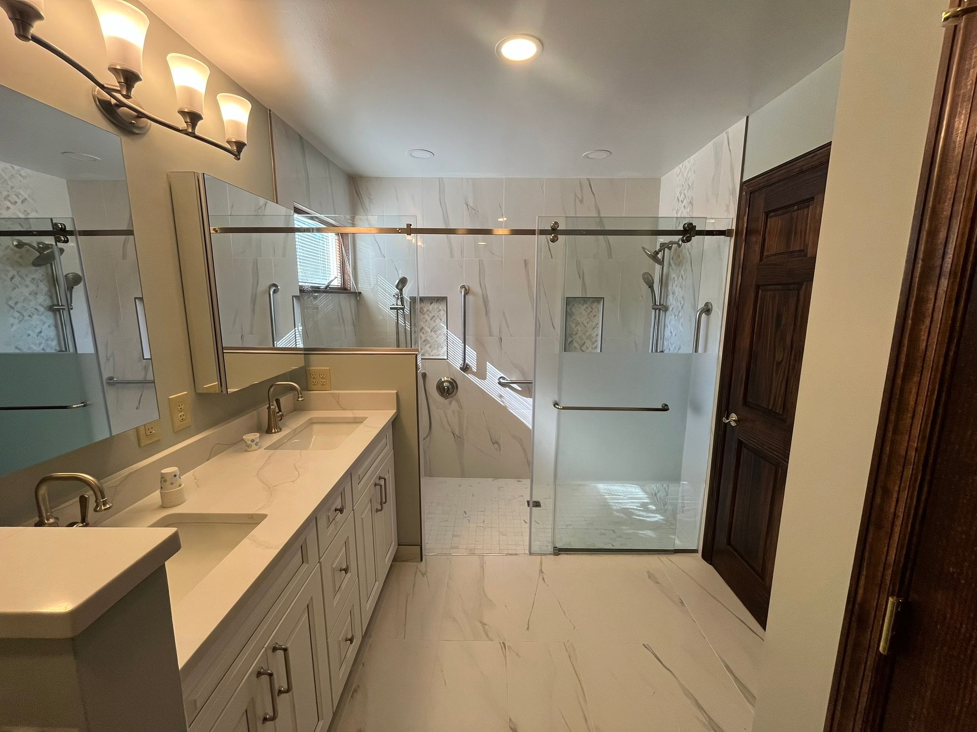 A bathroom with two sinks and a walk in shower.