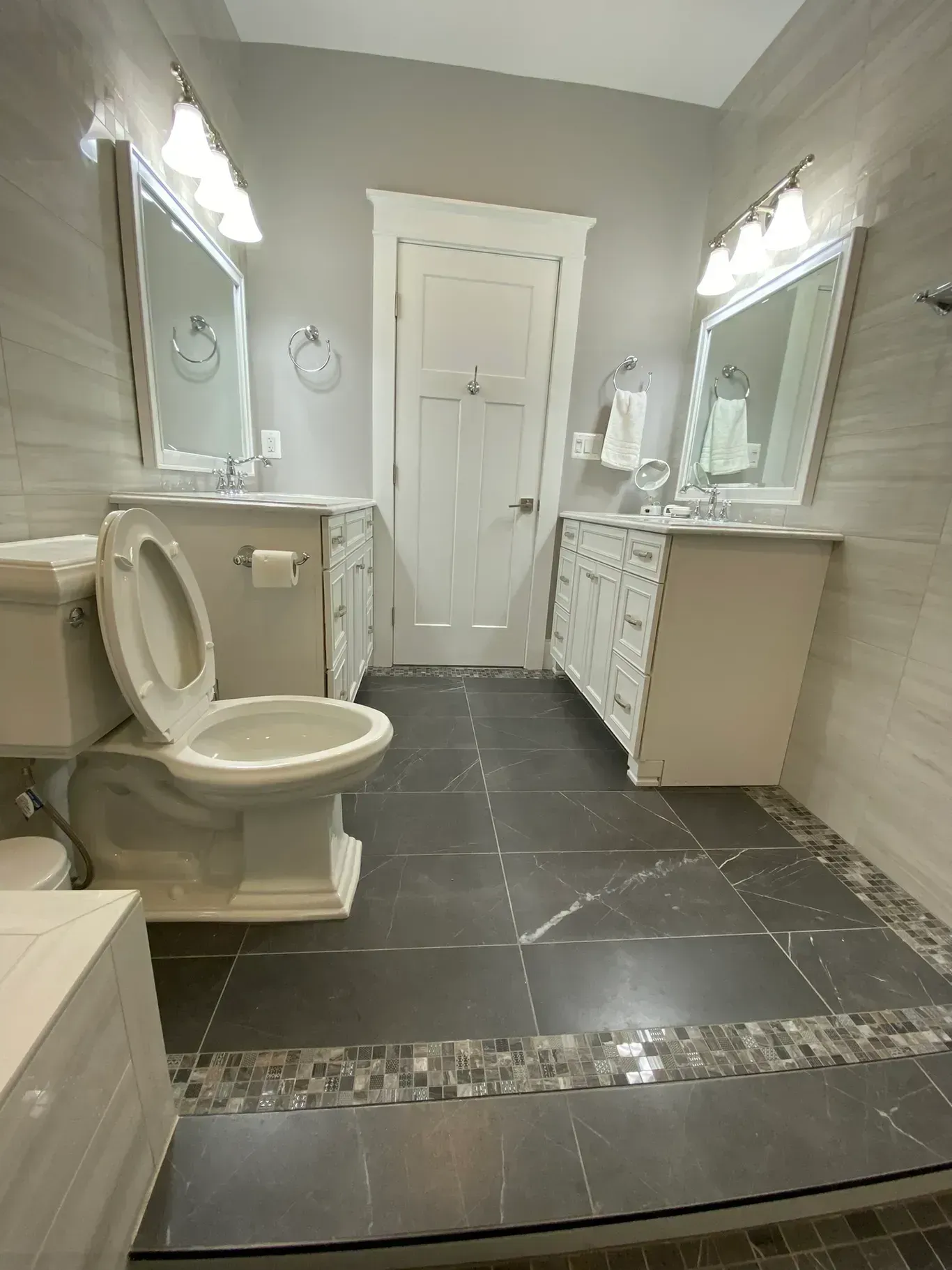 A bathroom with a toilet , sink and mirrors.