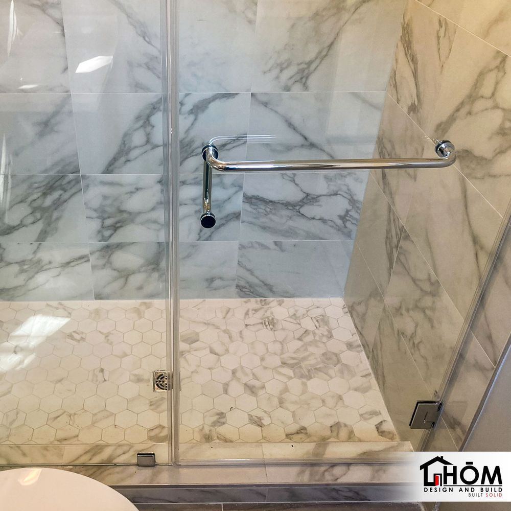A bathroom with marble walls and a glass shower door