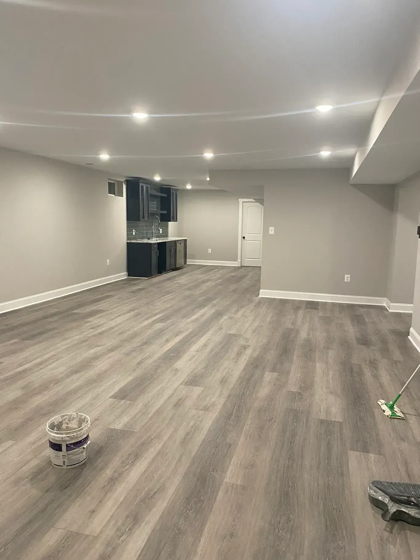 A large empty room with hardwood floors and a mop.