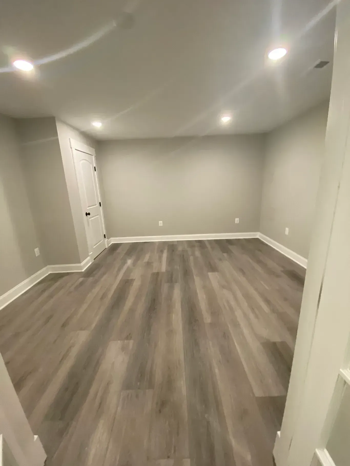 A large empty room with hardwood floors and gray walls.