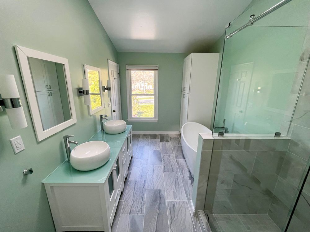 A bathroom with two sinks , a tub , and a walk in shower.