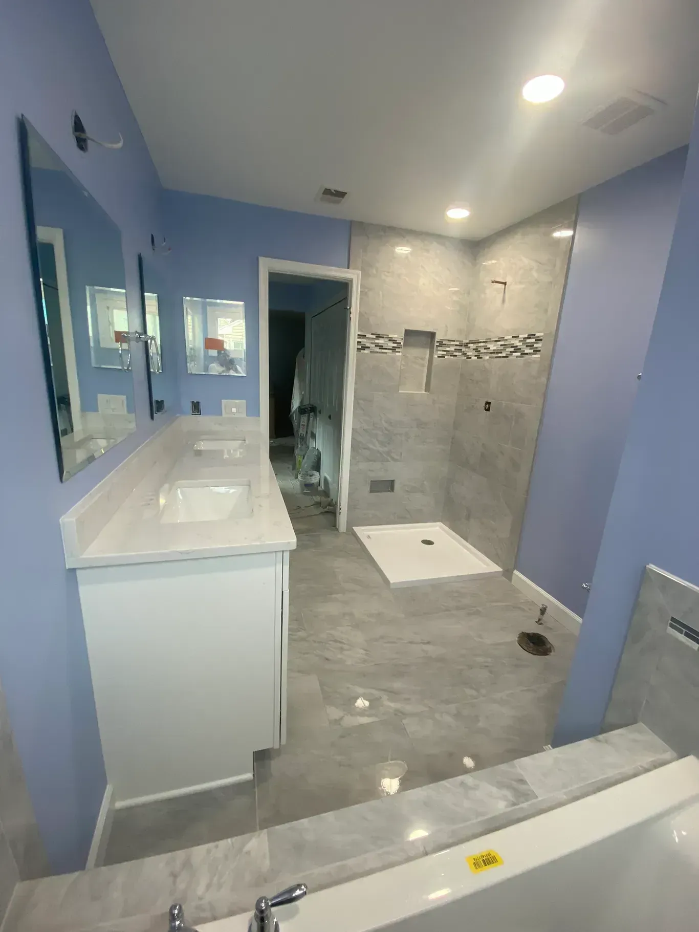 A bathroom with a tub , sinks , mirrors and a walk in shower.