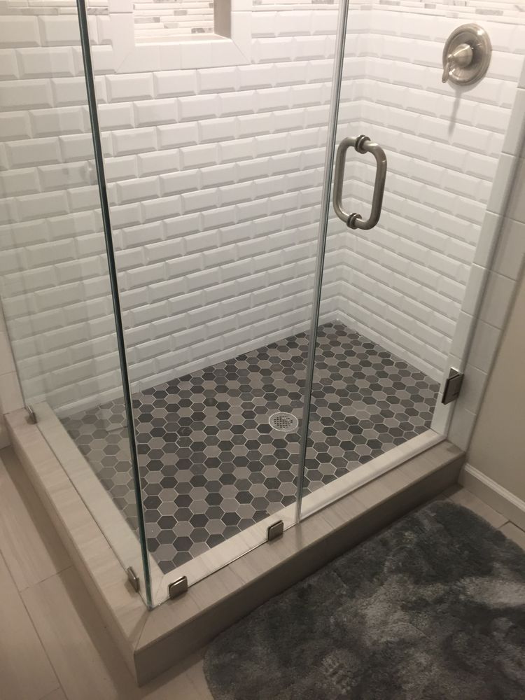 A bathroom with a walk in shower with a glass door.
