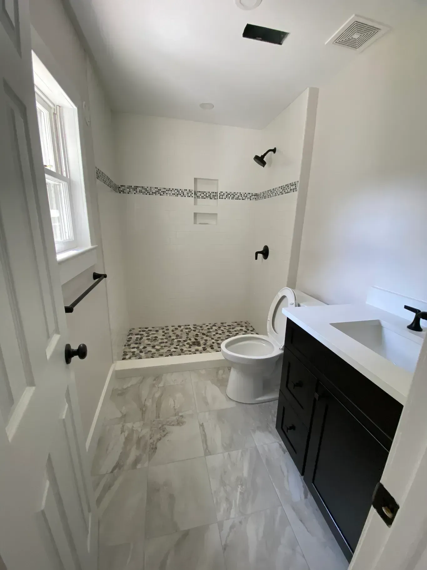 A bathroom with a toilet , sink and shower.