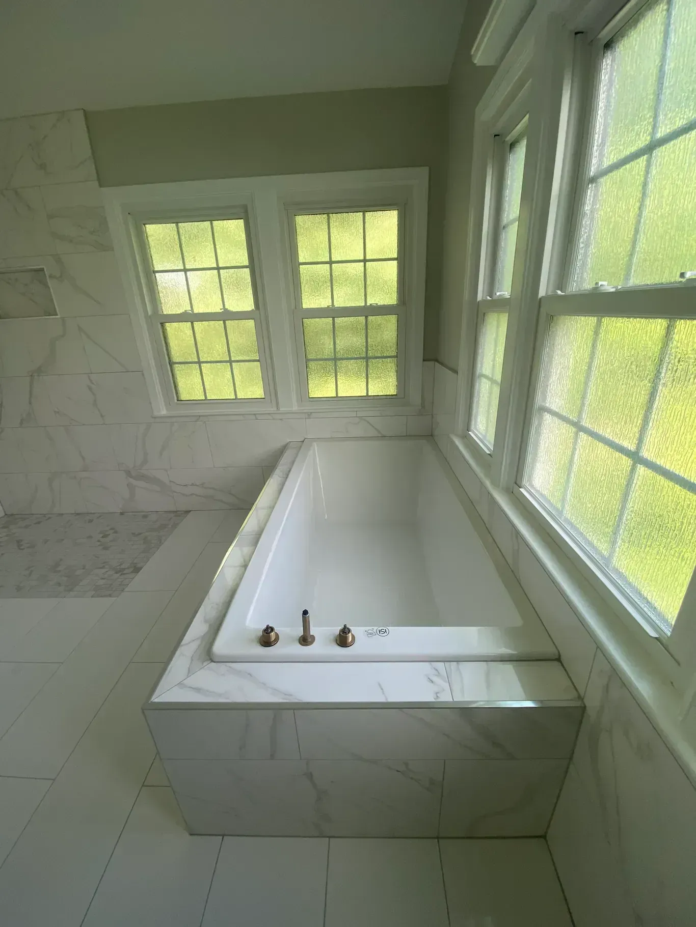 A bathroom with a jacuzzi tub and two windows.
