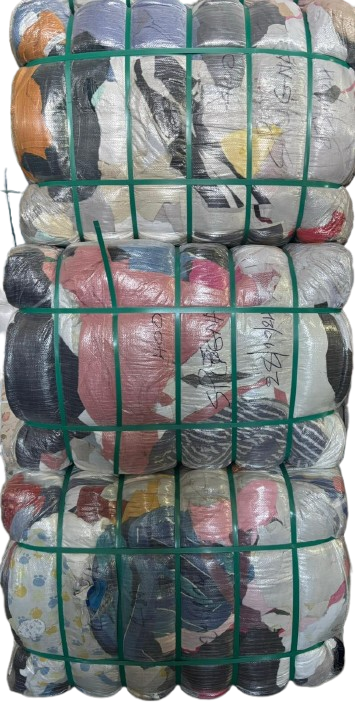 Sacchi impilati di bottiglie e contenitori di plastica assortiti, avvolti in una rete verde per il riciclaggio.