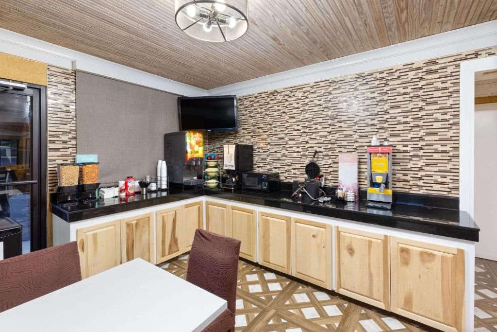 Breakfast buffet area in a hotel with countertop, cabinets, and a table with chairs.