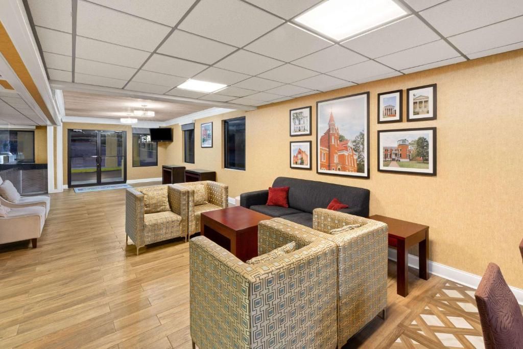 Lobby with seating, wood floors, framed art, and an exterior door. Beige, brown, and gray hues.