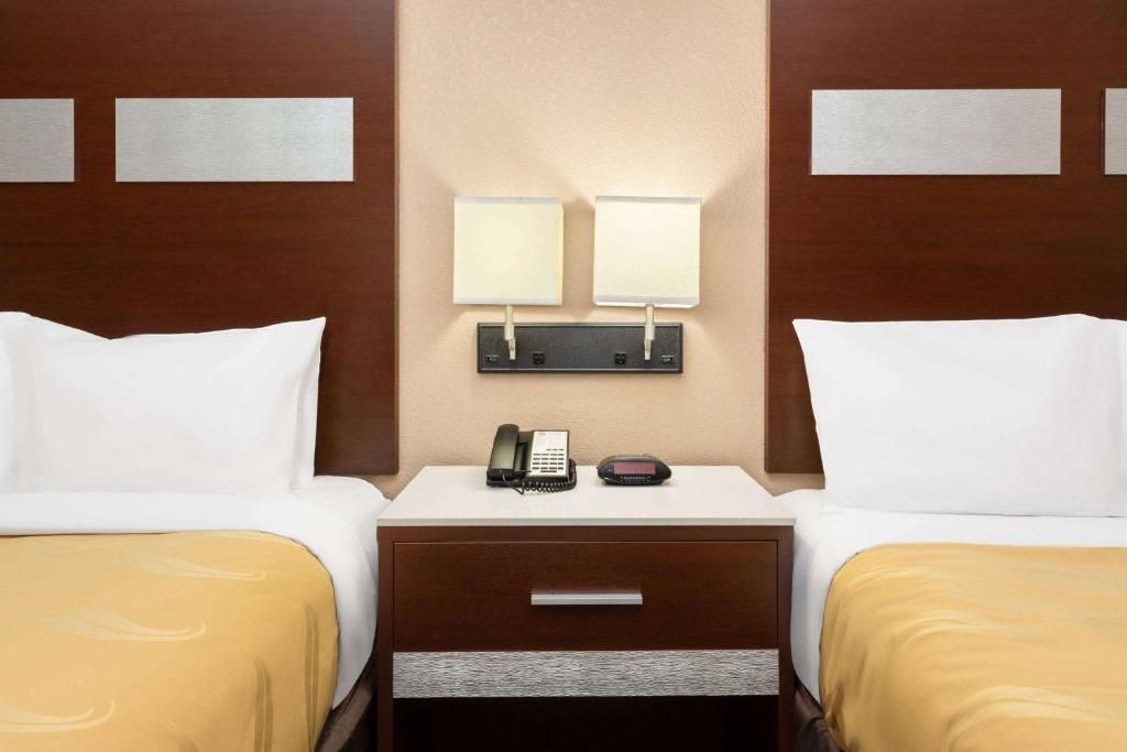 Hotel room with two twin beds, nightstand, lamps, and a phone.