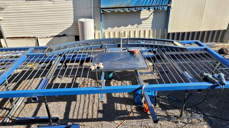 Blue metal roof frame on a gravel rooftop beside industrial HVAC units.