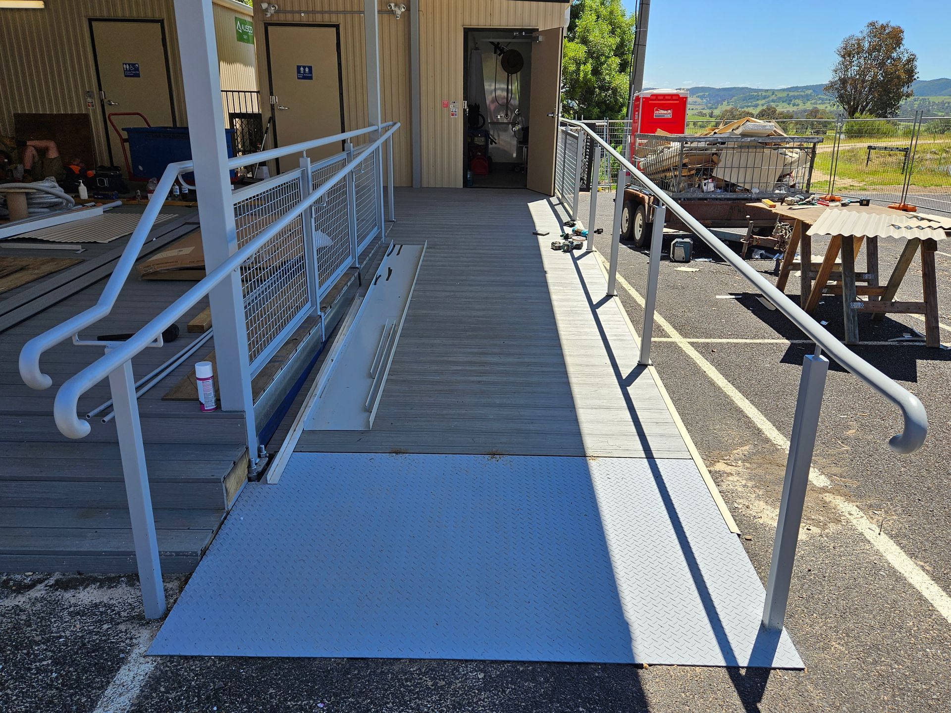 Accessible ramp entrance with handrails leading to a doorway beside an outdoor seating area