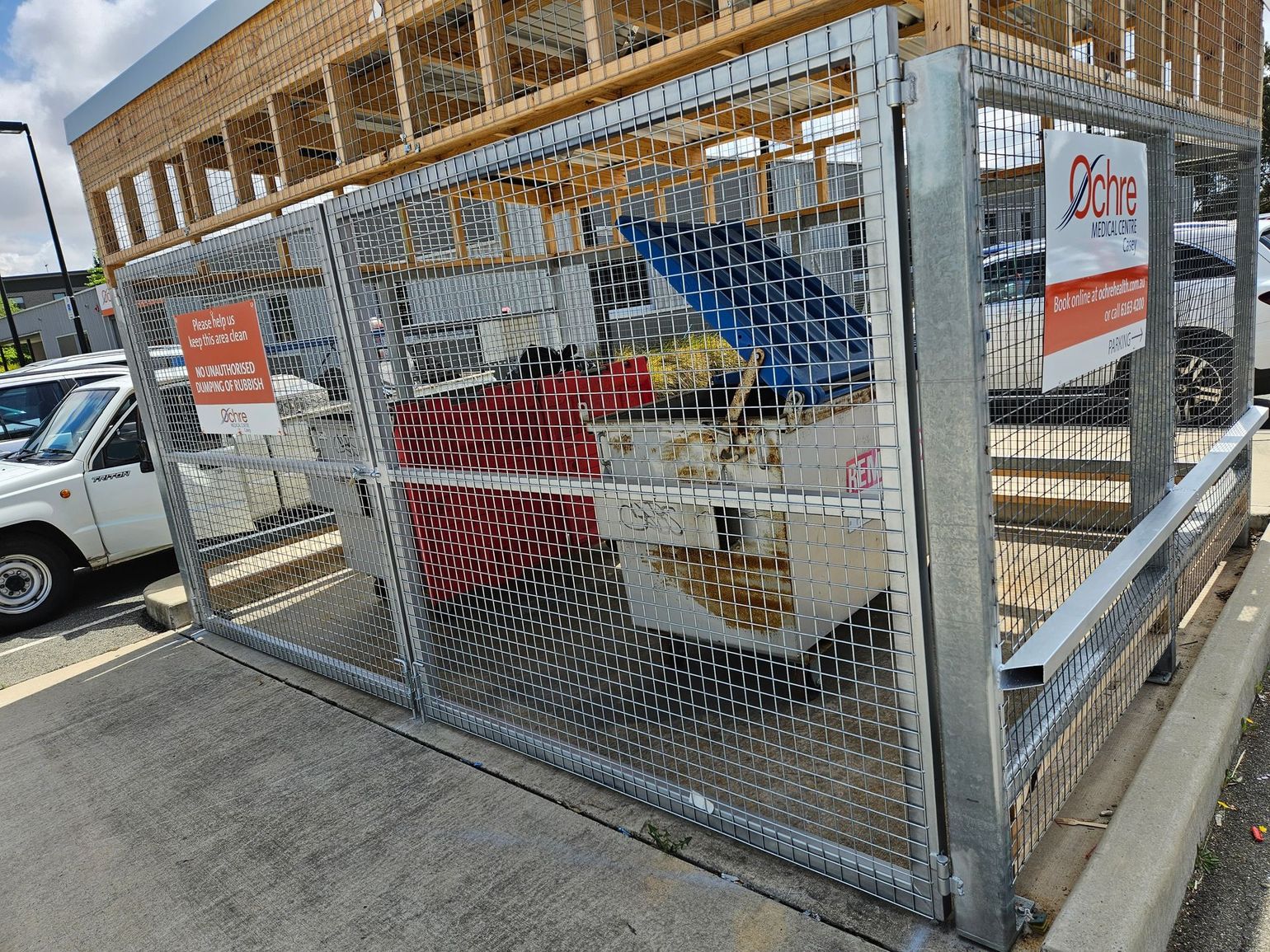 Chain-link enclosure around a construction site with lumber framing and a red lift inside