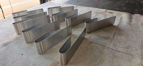 Rows of stainless steel bike racks on a concrete sidewalk outdoors