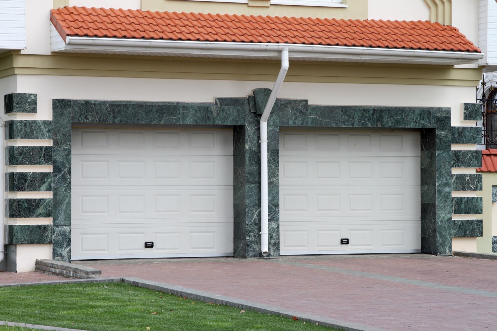 There are two garage doors on the side of a house.
