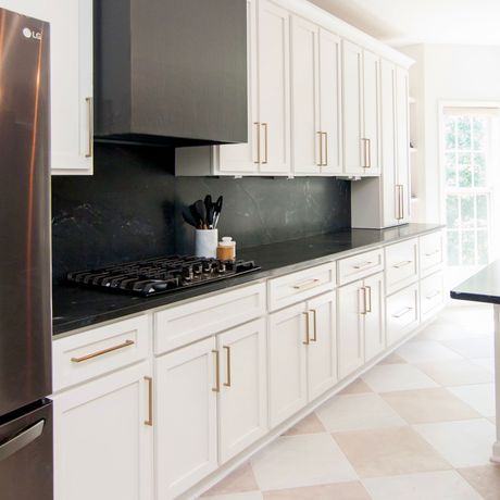 Bright modern kitchen with white cabinets, black backsplash, and stainless steel refrigerator