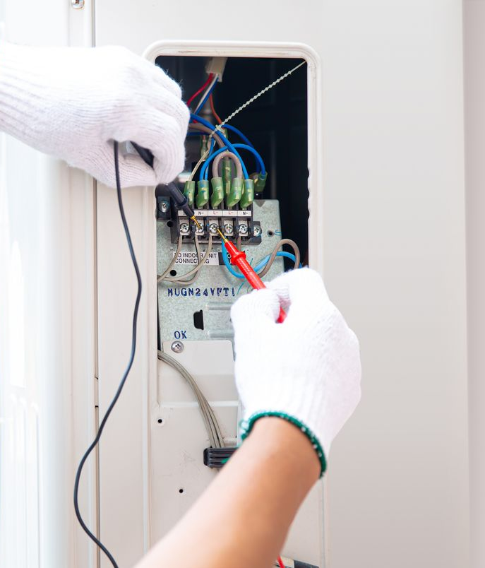 Gloved Hands Wiring an Open Electrical Panel With Red and Black Cables — Diverse Power In Newcastle, NSW
