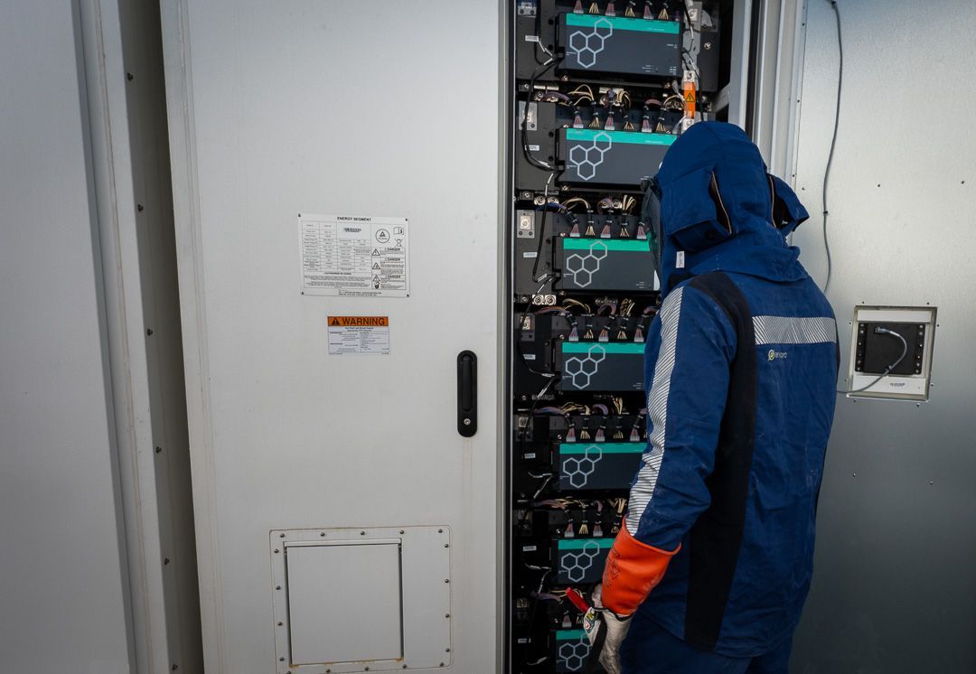 Technician in blue jacket inspecting server racks in a data center room